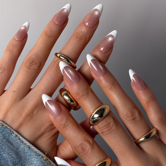 Close-up of hands with long, manicured nails and gold rings on a neutral background