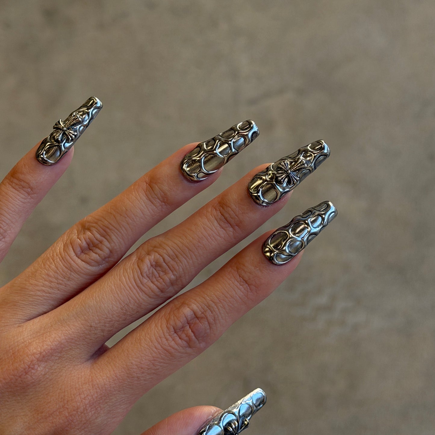 Hand with silver nail art designs on a neutral background