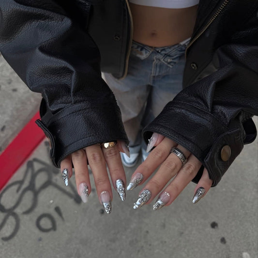Close-up of hands with decorative nails wearing black leather gloves on a street background with chrome nails