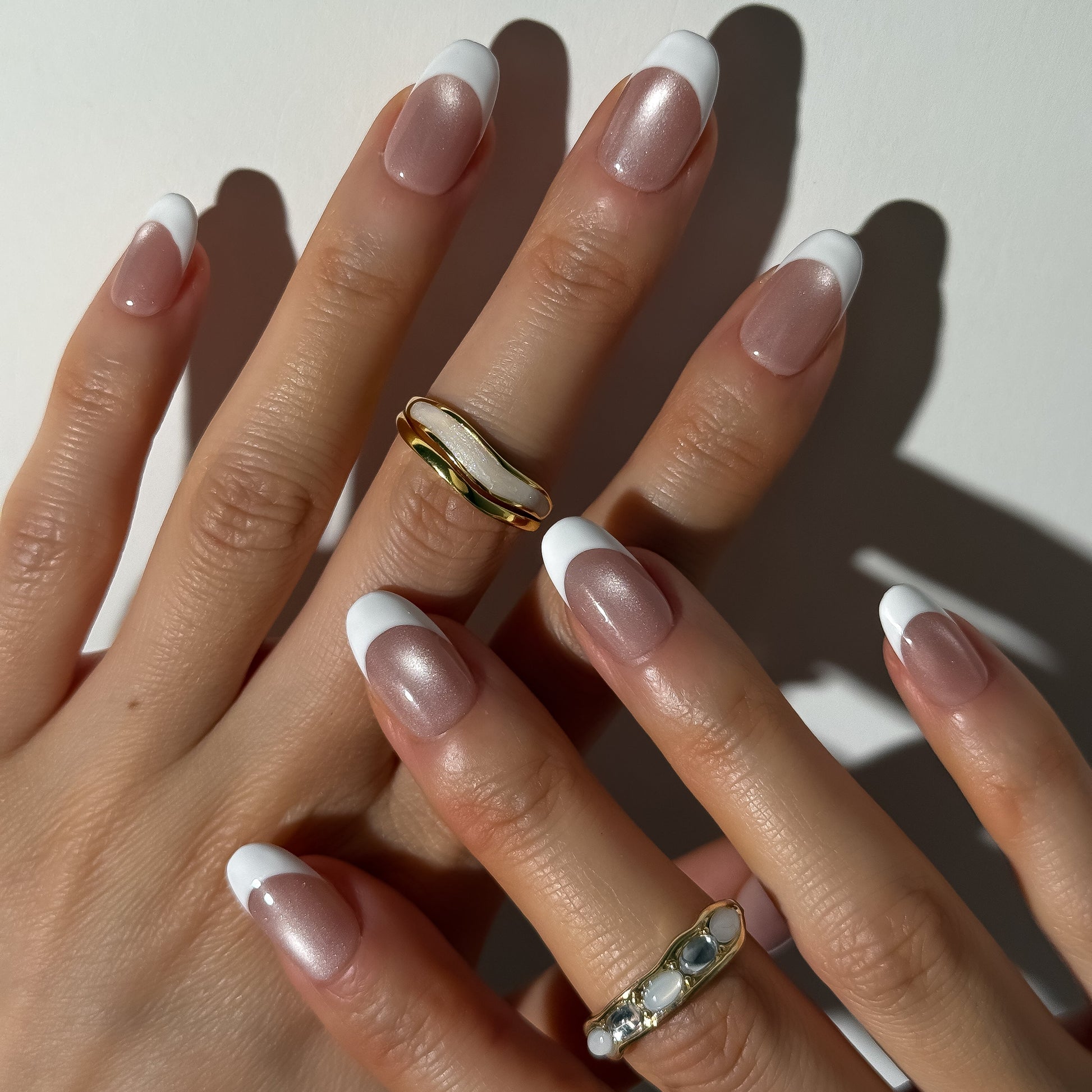 Close-up of hands with manicured nails and rings on a light background