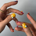 Close-up of hands with colorful nail polish on a neutral background