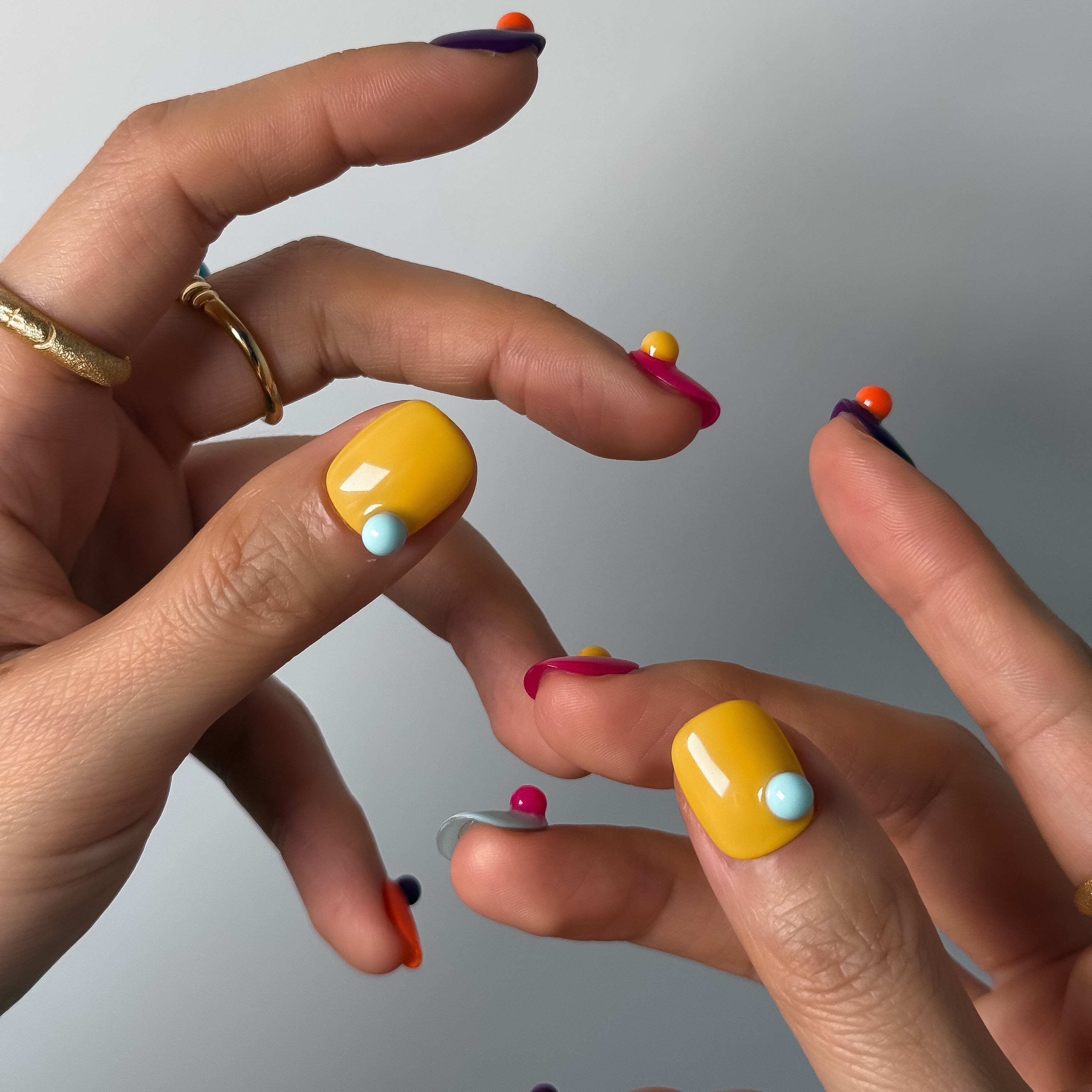 Close-up of hands with colorful nail polish on a neutral background