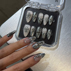 Set of silver and clear nail tips in a case with a hand displaying nails with similar design.