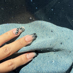 Hand with black and white patterned nails against a denim background