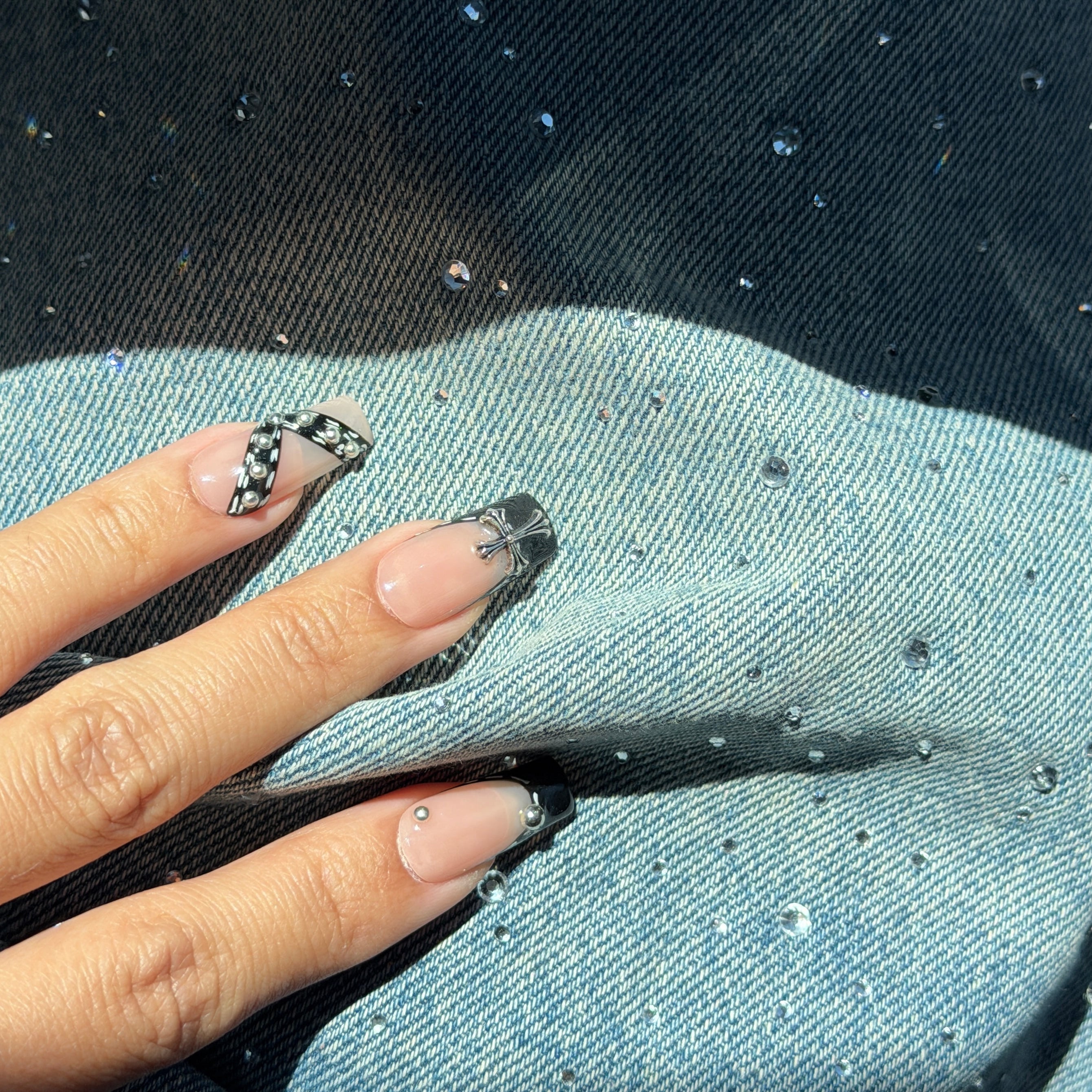 Hand with black and white patterned nails against a denim background