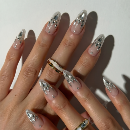 Close-up of hands with decorative nails and a gold ring on a light background